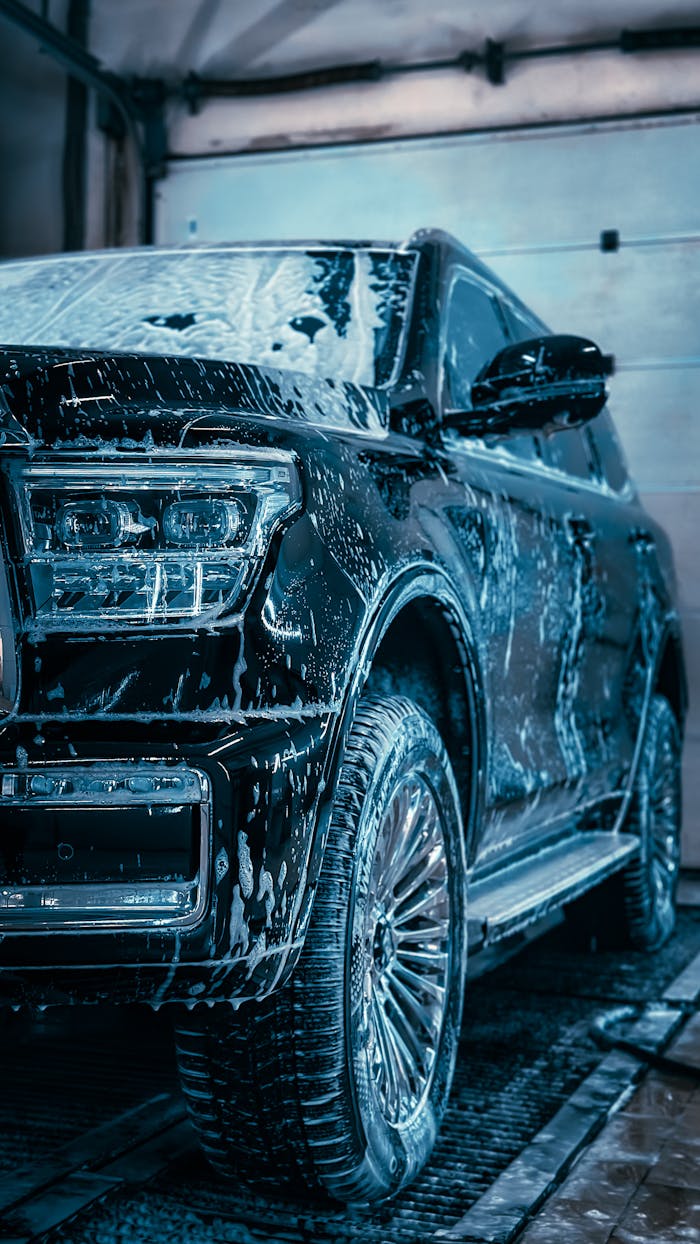 services-02 Close-up of a sleek SUV covered in soap during a car wash, highlighting cleanliness and care.