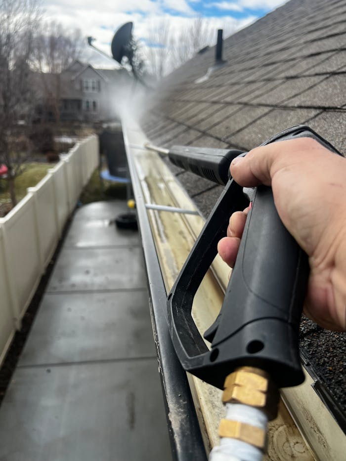 gallery-1 Close-up of gutter cleaning with pressure washer, outdoors, during the day.