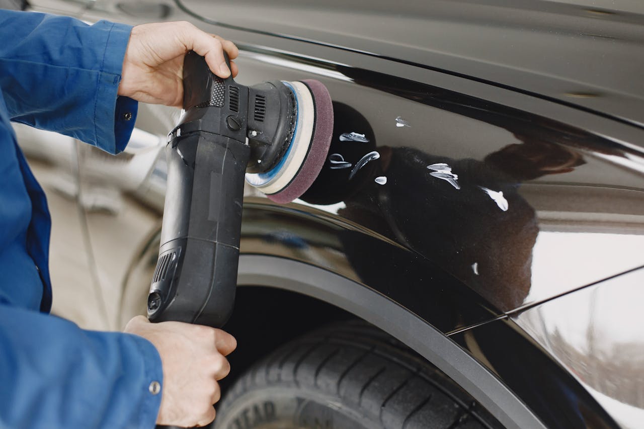 services-03 Hands using a polishing machine on a car's surface in a garage setting.